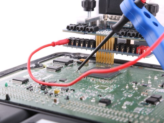 close up of green computer motherboard with hand solding stage chiptuning